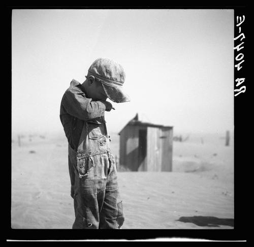 A boy protects his face from dust in Cimarron County, Okla., in 1936.