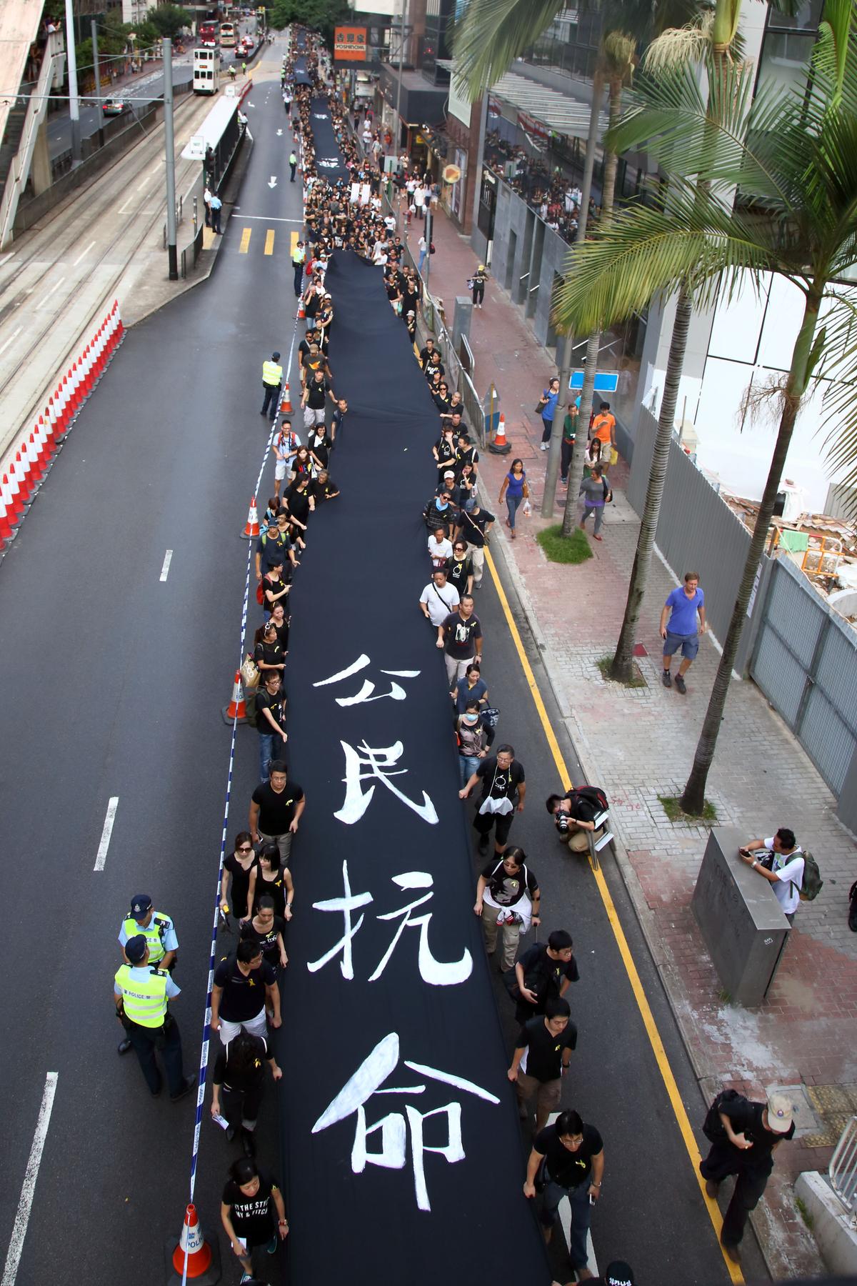 Protesters in black shirts hold a black banner that says "civil disobedience" in calling for universal suffrage in Hong Kong, on Sept. 14, 2014. 4000 supporters of Hong Kong's Occupy Central movement participated in the Black-Cloth March. (Pan Zaishu/Epoch Times)