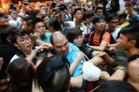 A man (C) pushes towards pro-democracy protesters while several protesters try to hold him back in the Mong Kok district in Hong Kong on Oct. 4, 2014. (Song Xianglong/Epoch Times)