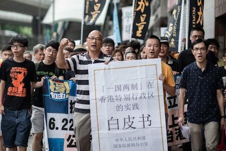 Demonstrators shout slogans, holding a large reproduction of Beijing's white paper, as they march toward Beijing's representative office in Hong Kong on June 11. China released a white paper document Tuesday emphasizing its control over Hong Kong. (Philippe Lopez/AFP/Getty Images)