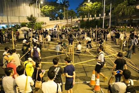 Pro-democracy protesters build a large barricade with bamboo in retaliation after an earlier incident today where opponents of the occupy movement tried to remove them near the government headquarters in Hong Kong on Oct. 13, 2014. (Benjamin Chasteen/Epoch Times)