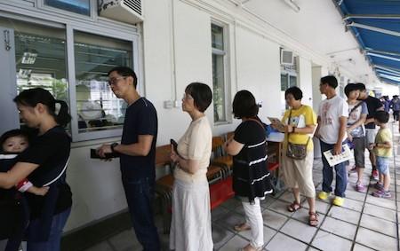 People queue up at a polling station on the last day to vote for an unofficial referendum on democratic reform in Hong Kong Sunday, June 29, 2014. (AP Photo/Kin Cheung)