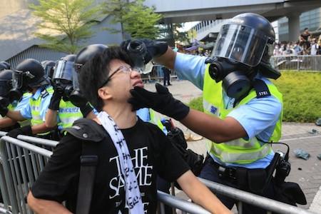 On Sept. 29, a policeman in front of government headquarters took out his own water bottle and washed the eyes of the protester who he had just hit with pepper spray. (Yu Gang/Epoch Times)