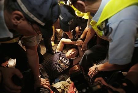 A man is cuffed by police and taken from the confrontation of pro-democracy student protesters and angry local residents in Mong Kok, Hong Kong, Friday, Oct. 3, 2014. (AP Photo/Wally Santana)