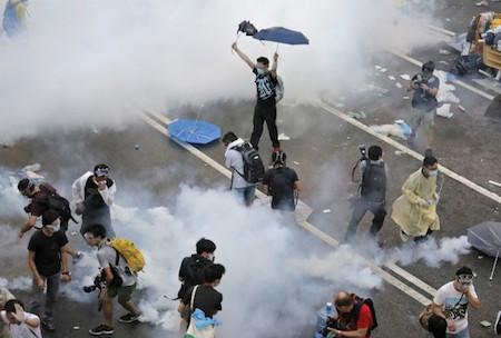 Protesters walk through tear gas used by riot police against protesters after thousands of people blocked a main road at the financial central district in Hong Kong, Sunday, Sept. 28, 2014. (AP Photo/Vincent Yu)
