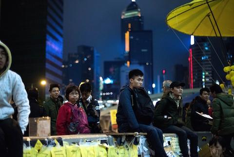 People sit on a wall as they listen to a speaker at the movement's main protest site in the Admiralty district of Hong Kong on December 6, 2014. (Johannes Eisele/AFP/Getty Images)
