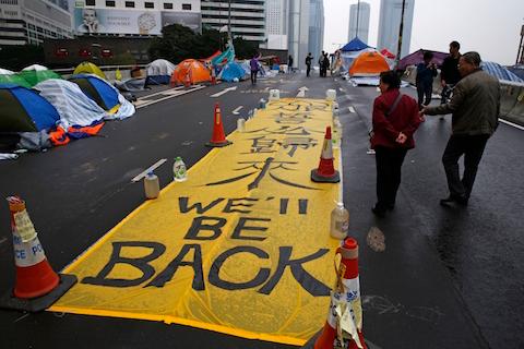 A yellow banner reading "We'll be back" is displayed by protesters at the occupied area outside government headquarters in Hong Kong Wednesday, Dec. 10, 2014. (AP Photo/Kin Cheung)