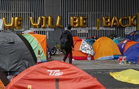 A man walks past protesters' tents on a main road at the occupied area outside government headquarters in Hong Kong Wednesday, Dec. 10, 2014. (AP Photo/Kin Cheung)