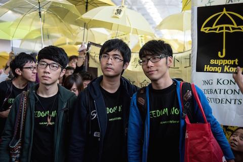 Student leaders Alex Chow (C), Nathan Law (L) and Eason Chung (R) are surrounded by pro-democracy protesters at the Hong Kong international airport before their scheduled flight to Beijing on November 15, 2014. (Alex Ogle/AFP/Getty Images)