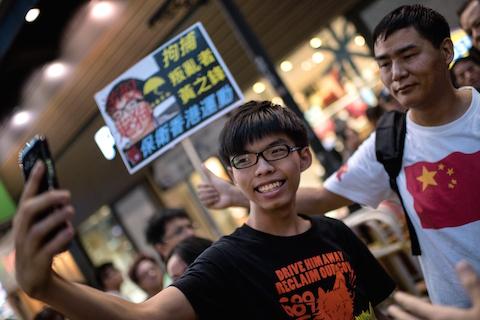 Hong Kong student leader Joshua Wong (C) takes a "selfie" next to a pro-Beijing activist (R) who had been shouting slogans at Wong as he handed out flyers in support of the Hong Kong pro-democracy protests, in the Causeway Bay area of Hong Kong on November 16, 2014. (Alex Ogle/AFP/Getty Images)