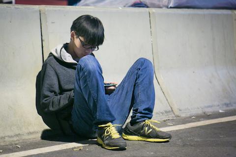 Student leader Joshua Wong sits just outside the Citic Tower area at the Admiralty protest site on Nov. 17, 2014. (Benjamin Chasteen/Epoch Times)