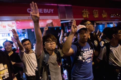 Pro-democracy protesters  flash the three-finger salute from the 