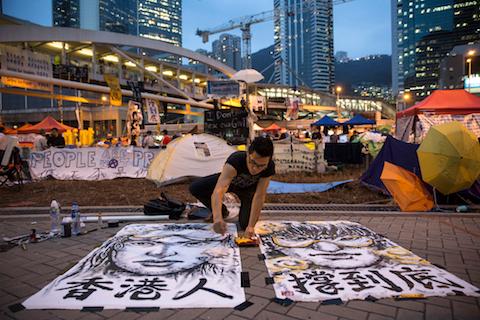 Artist Brian Chui who is a design consultant visiting from New York paints a female protester at the main protest site at Admiralty Oct. 24, 2014, in Hong Kong. (Paula Bronstein/Getty Images)