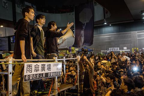 Student leader and pro-democracy activist Joshua Wong (2L) listens to speeches on stage during a rally on the streets outside Hong Kong's Central Government Complex on Nov. 21, 2014, in Hong Kong. (Chris McGrath/Getty Images)