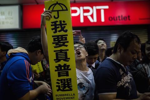 A pro-democracy protester (C) holds a sign for the Umbrella Movement as he shouts slogans in the Mongkok district of Hong Kong on Nov. 28, 2014. (Anthony Wallace/AFP/Getty Images)