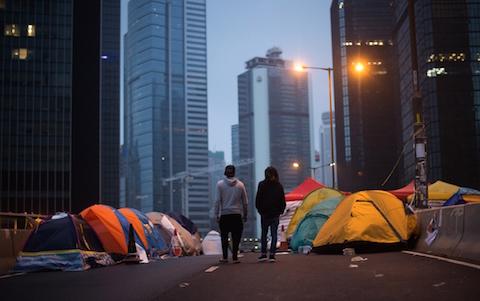 Two pro-democracy protestors walk at the movement's main protest site in the Admiralty district of Hong Kong early on Dec. 3, 2014. (Johannes Eisele/AFP/Getty Images)