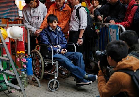 Student leader Joshua Wong attends a news conference as he sits on a wheel chair during a hunger strike at the occupied area outside government headquarters in Hong Kong on Friday, Dec. 5, 2014. (AP Photo/Kin Cheung)