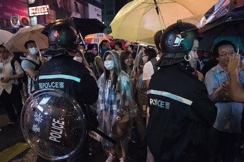 Pro-democracy protesters stand their ground under a rain infront of riot policemen in the Mongkok district of Hong Kong on October 22, 2014. (Nicolas Asfouri/AFP/Getty Images)