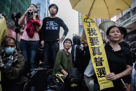 Civic Party lawmaker Claudia Mo (C) stand with pro-democracy protesters on a makeshift stage as bailiffs remove tents under a court injunction in the Mongkok district of Hong Kong on November 25, 2014. (Philippe Lopez/AFP/Getty Images)