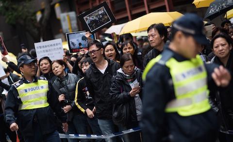 Demonstrators speak to a police officer in a march against police brutality during the pro-democracy protests, in the Wan Chai district of Hong Kong on December 7, 2014. (Johannes Eisele/AFP/Getty Images)
