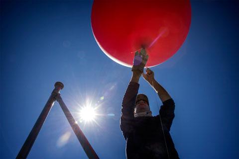 The Balloon Rig: Gulf Restoration Network's Scott Eustis launches the six-foot weather balloon over West Bay. The balloon will carry the dual-camera chassis about 2,000 feet above the delta. (Edmund D. Fountain for ProPublica/The Lens)