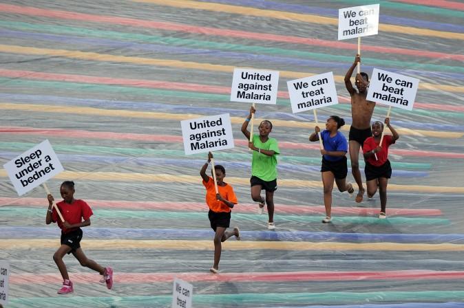 Children run with advertising banners for the fight against malaria. (Photo credit should read Alexander Joe/AFP/Getty Images)