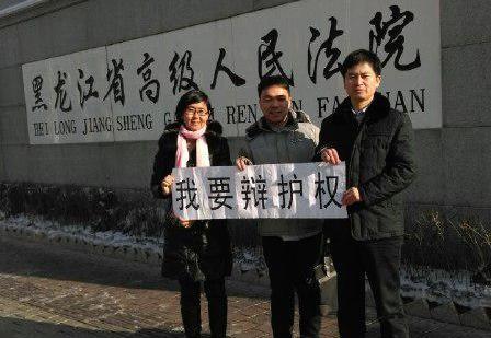 Lawyer Wang Yu (L), lawyer Zhang Weiyu (R), and Zhang's assistant Ren Feixiang (C) hold a banner that says "I want the right to defend" in front of the Heilongjiang Provincial Supreme People's Court after filing a complaint about the secret trial of Falun Gong practitioners, on Jan. 8, 2014. (Epoch Times)