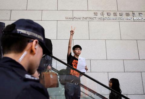 Student leader Joshua Wong flashes victory sign as he arriving at the police headquarters in Hong Kong, Friday, Jan. 16, 2015. (AP Photo/Vincent Yu)