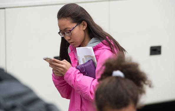 A teenager looks at her smartphone outside the Natural History Museum in Washington on April 8, 2015. (AFP/Getty Images)