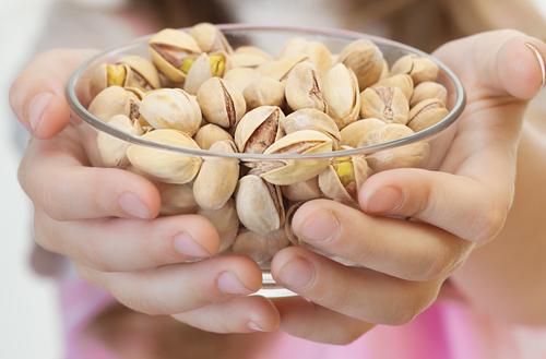 Nuts tend to be low in carbs, but high in fat, fiber, protein and various micronutrients. (<a href="http://www.shutterstock.com/pic-102461516/stock-photo-little-girl-in-pink-dress-holding-bowl-with-pistachios-isolated-on-white-background.html?src=agV3woFIjHZwmte4LIkhyg-1-131" target="_blank">Shutterstock</a>)