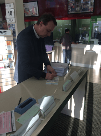 Lawyer Kerry Gore prepares the package of the criminal complaint against Jiang Zemin for an express delivery at a post office in New Zealand. (Courtesy of Kerry Gore)