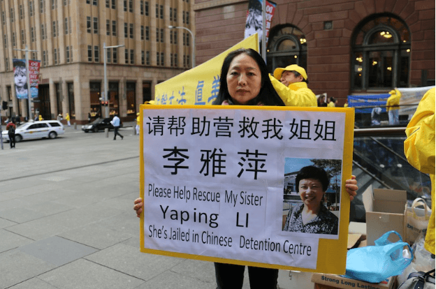 Mrs Ying Li holds a placard asking for the public's help to rescue her sister, Yaping Li, who was illegally arrested five months ago, in China, for practising Falun Gong. (Melanie Sun/Epoch Times)