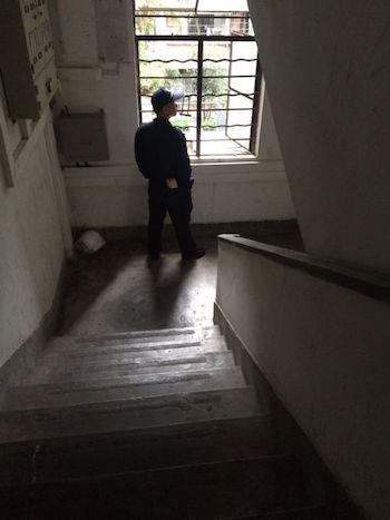 A Chinese public security officer keeps a lookout for Falun Gong practitioner Li Qiong at the stairwell of her apartment block. The photo was taken on July 8, 2015 by Ms. Li's sister. (Photo provided by Li Qiong)