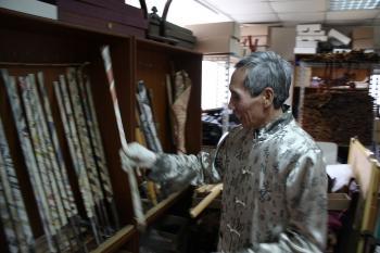 Chen laughs as he puts back one of his incomplete swords into the rack, on the left. Wrapped in newspaper in his attic, each is worth thousands. (Matthew Robertson/The Epoch Times)