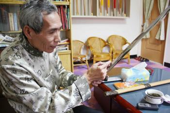 Chen Shih-Tsung, over 60 years old, explains the chemical reactions crucial to successful swordmaking. (Matthew Robertson/The Epoch Times)
