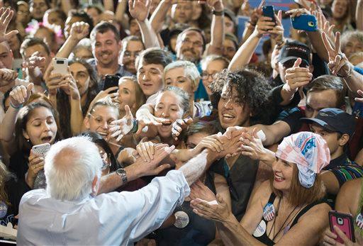Supporters of Democratic presidential candidate Sen. Bernie Sanders, I-Vt., reach to shake his hand at a rally, Sunday, Aug. 9, 2015, at the Moda Center in Portland, Ore. (AP Photo/Troy Wayrynen)