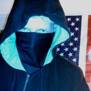 DigitaShadow, an operations director of the hacker group GhostSec, stands in front of an American flag. The organization is fighting ISIS online. (GhostSec)