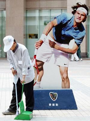 A street cleaner sweeps in front of the oversized image of tennis player Roger Federer (Getty Images)