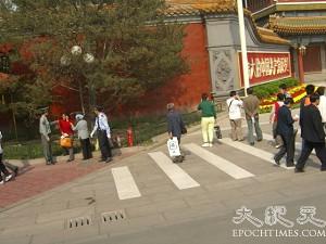 A policeman interrogating pedestrians in front of the Xinhua Gate. (The Epoch Times)