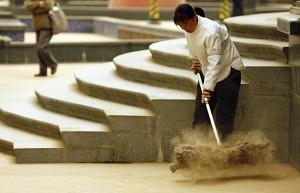 A cleaner clears away sand from an overnight sandstorm originating on the border of China and Mongolia which covered Beijing, 17 April 2006. Millions of Beijing residents woke up to find their city covered in sand -- another reminder that the desert is moving closer to the Chinese capital. (Peter Parks/AFP/Getty Images)