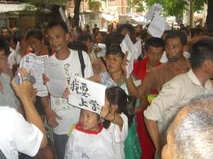 A young petitioner holds a sign reading, "I want to go to school." (The Epoch Times)