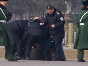 Police beat a man while shielding onlookers from seeing. (Minghui Net)