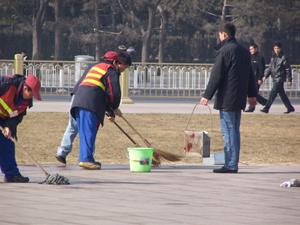 Workers wash away the blood stains. Their portable trash bins are covered with blood. (Minghui Net)