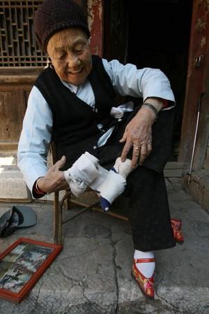 An elderly woman binds her feet in a long strip of silk cloth. (Getty Images)