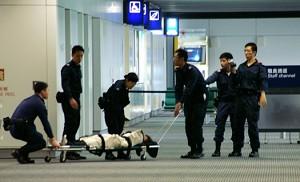 Wrapped up in a police blanket, a Falun Gong adherent is being taken to the plane. (Epoch Times)