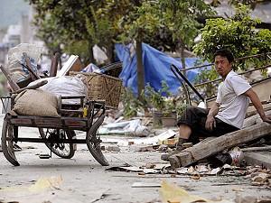 A man sits beside his damaged tricycle on a street in Leigu Town of Beichuan County in China's southwestern province of Sichuan on May 27, 2008. (Liu Jin/AFP/Getty Images)