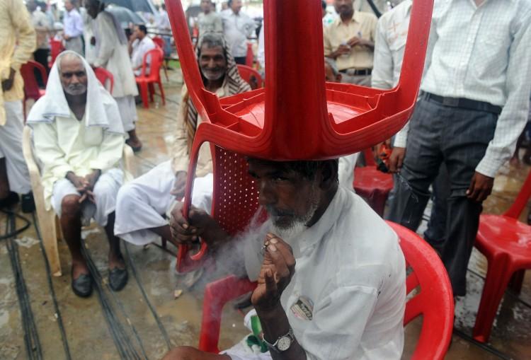 <a><img class="size-large wp-image-1768978" title="A farmer smokes a cigarette whilst sheltering from the rain under a chair in a political rally few years ago. The Indian government enacted tobacco ban in 2003 that makes smoking in public places an offense. (PRAKASH SINGH/ Getty Images)" src="https://www.theepochtimes.com/assets/uploads/2015/09/118807800.jpg" alt="" width="590" height="400"/></a>