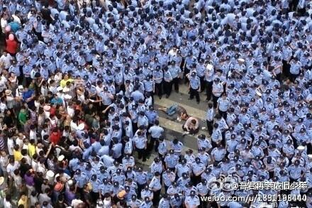 An incapacitated, or worse, protester is accompanied by a peer, surrounded by riot police, in Qidong, Jiansu Province, China, on July 28. (Weibo.com)
