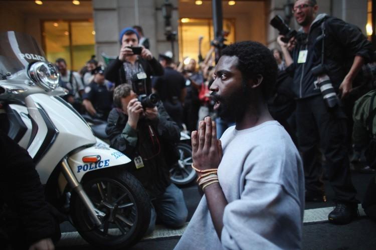 <a><img src="https://www.theepochtimes.com/assets/uploads/2015/09/129214728ii.jpg" alt="A man associated with the Occupy Wall Street movement prays in front of police vehicles before being arrested in the financial district on October 14, 2011 in New York City. (Spencer Platt/Getty Images)" title="A man associated with the Occupy Wall Street movement prays in front of police vehicles before being arrested in the financial district on October 14, 2011 in New York City. (Spencer Platt/Getty Images)" width="575" class="size-medium wp-image-1796395"/></a>
