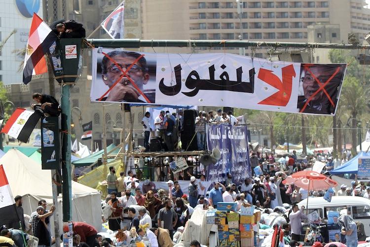 <a><img class="size-large wp-image-1788399" title="Egyptians sit on the traffic light decorated with a banner showing the portraits of former prime minister Ahmed Shafiq (R) and former Arab League general secretary Amr Mussa and which reads in Arabic 'no for the reminisce of the old regime', as thousands gather during a rally in Cairo's Tahrir Square on April 20 (Khaled Desouki/AFP/Getty Images)" src="https://www.theepochtimes.com/assets/uploads/2015/09/Egypt143166390.jpg" alt="" width="590" height="393"/></a>